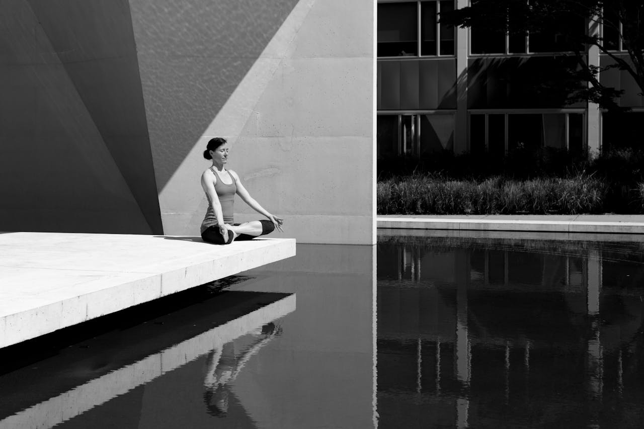 about-me-02 A woman meditating by a poolside, reflecting tranquility and focus in a minimalist setting.